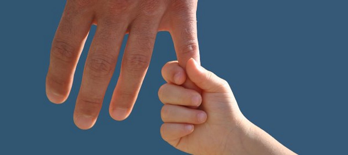 Kind greift Erwachsenenhand an kleinem Finger