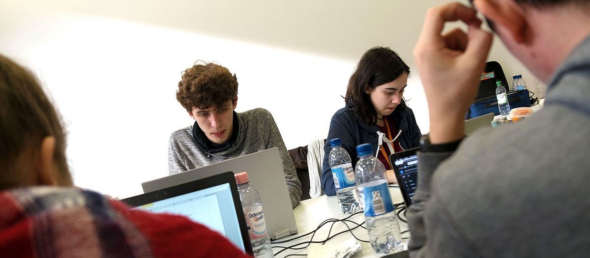Jugendliche mit Laptops an einem Tisch in einem Gruppenraum