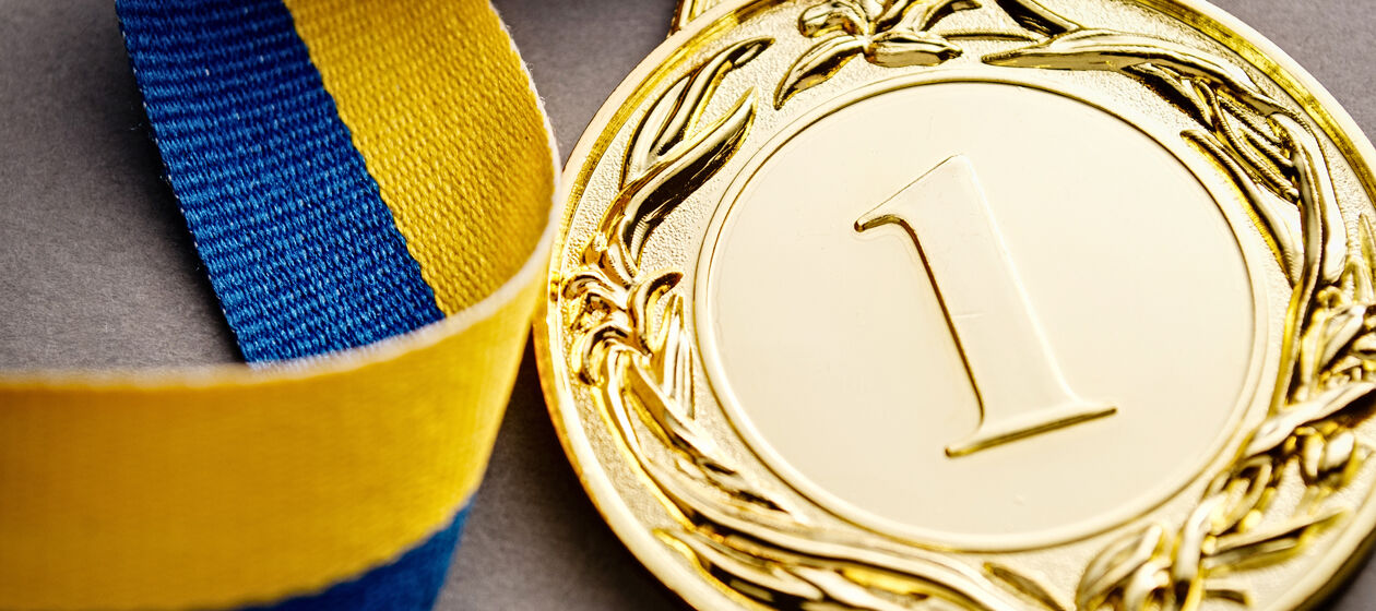Goldmedaille mit gelb-blauem Band liegt auf einem Tisch