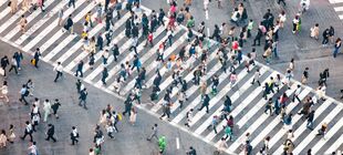 Zahlreiche Fußgänger überqueren eine große Straßenkreuzung in Tokyo
