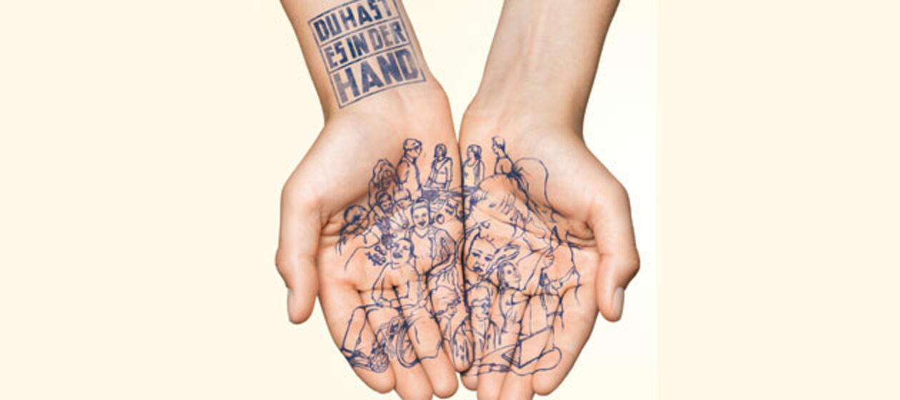 Zwei geöffnete Hände, tätowiert mit Menschen und dem Motto-Schriftzug des Wettbewerbs 2014 "Du hast es in der Hand" auf dem Handgelenk