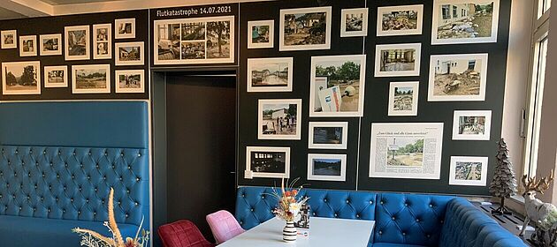 An einer Wand im Restaurant der Jugendherberge Bad Neuenahr-Ahrweile hängen gerahmte Fotos und Zeitungsartikel zur Flutkatastrophe im Juli 2021.