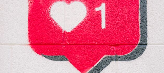 An eine Wand ist eine Sprechblase gemalt, in der ein Herz und die Zahl Eins zu sehen sind