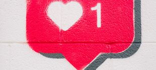 An eine Wand ist eine Sprechblase gemalt, in der ein Herz und die Zahl Eins zu sehen sind