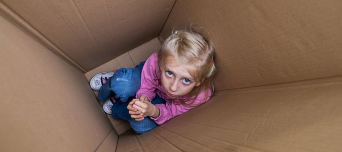 Ein kleines Mädchen hockt in einer Kiste