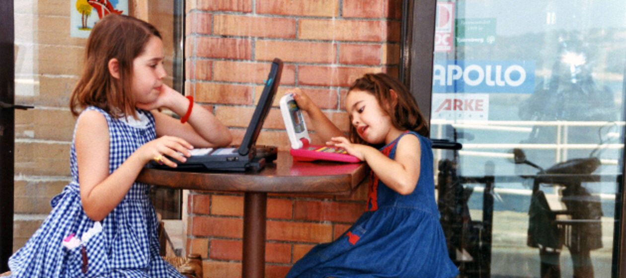 Zwei Mädchen sitzen am Tisch an ihren Laptops