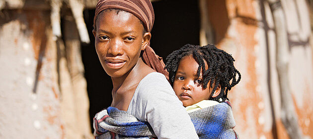 Afrikanische Mutter trägt ihr Kind in Tuch auf Rücken