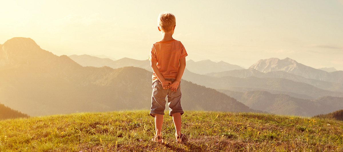 Kind auf einem Berg schaut in die Natur