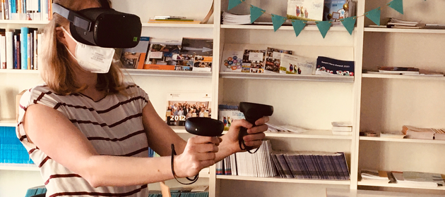 Eine junge Frau mit VR-Brille erlebt den virtuellen Raum.