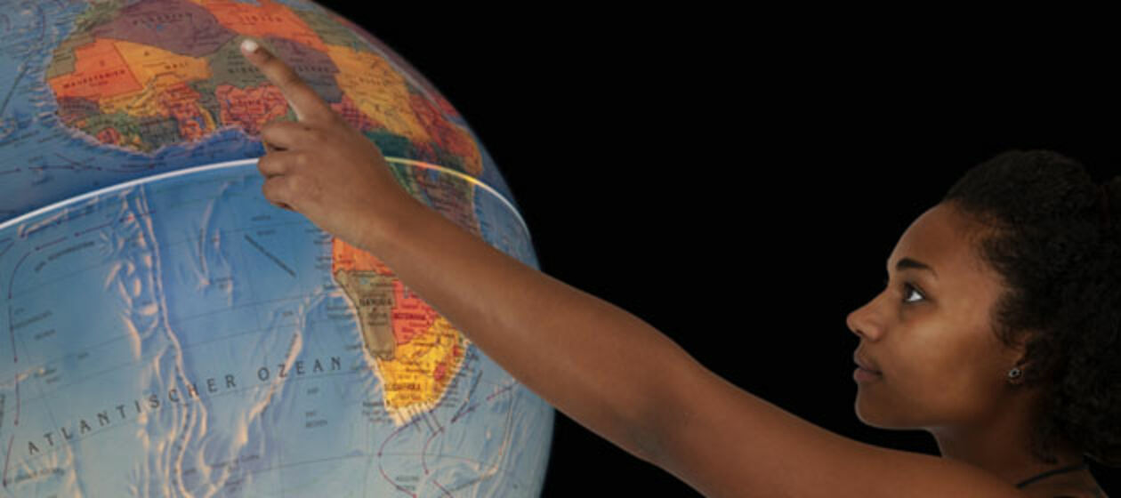 Eine junge Schwarze zeigt auf dem Globus auf Afrika