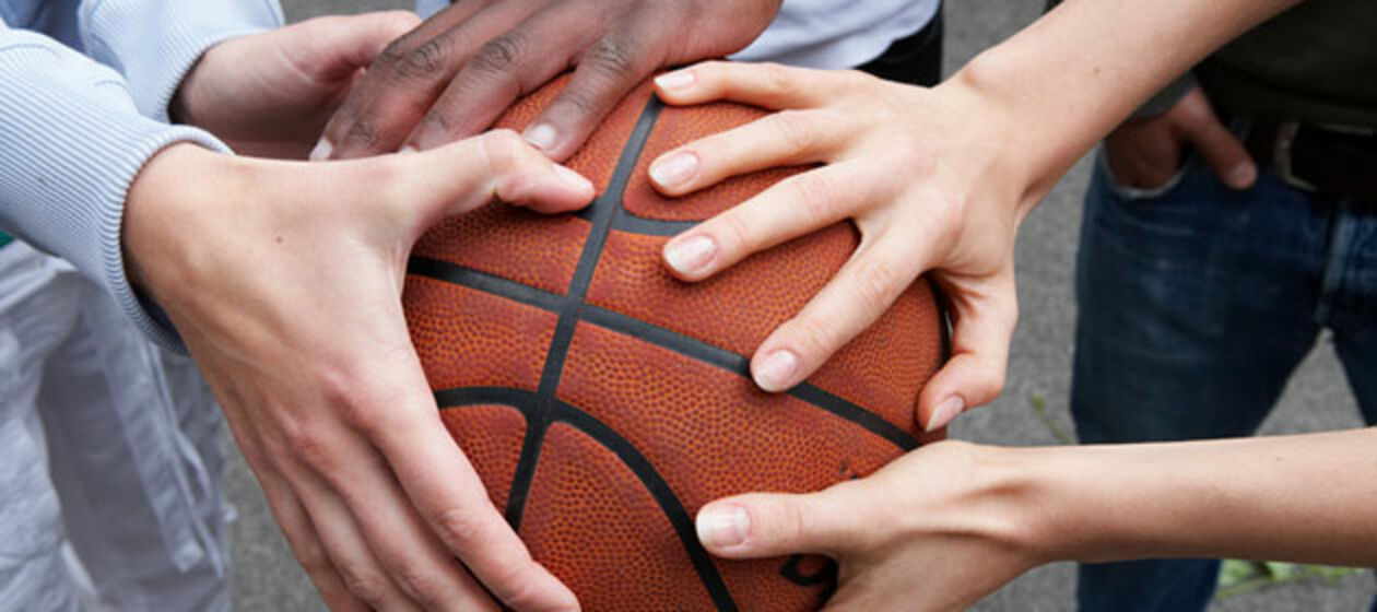 Mehrere Hände halten einen Basketball