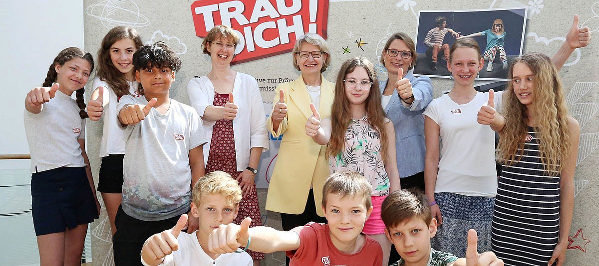 Politikerinnen und Kinder vor einem Banner der Initiative "Trau dich!"