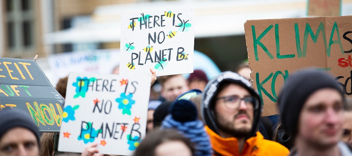 Demonstranten halten Schilder hoch für Klimaschutz