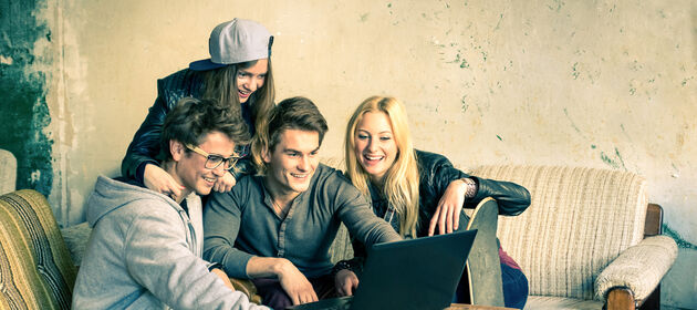 Ein Gruppe Jugendlicher sitzt vor einem Laptop