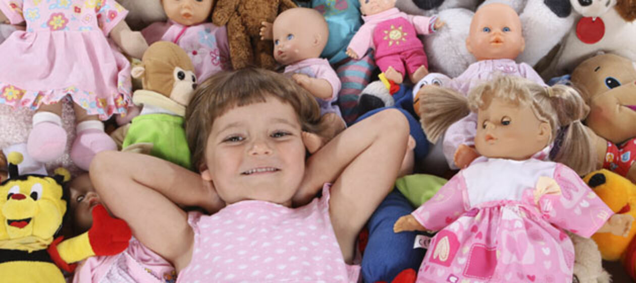 Ein Mädchen liegt inmitten von Puppen