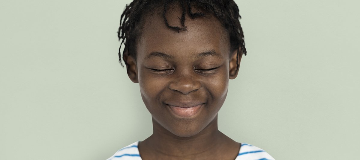 Lächelndes Kind dunkler Hautfarbe mit geschlossenen Augen