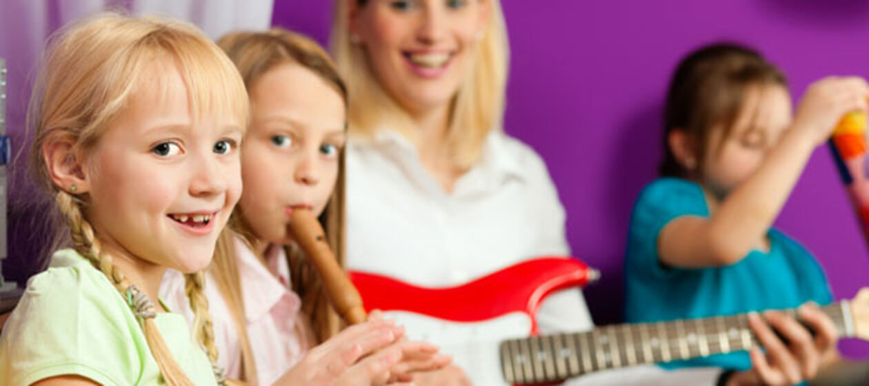 Kinder musizieren gemeinsam mit einer Lehrerin