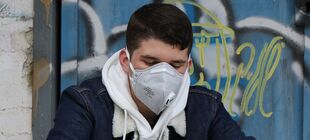 Jugendlicher mit Atemschutzmaske schaut zu Boden