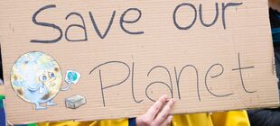 Schild mit einer weinenenden Erde und der Aufschrift Save Our Planet