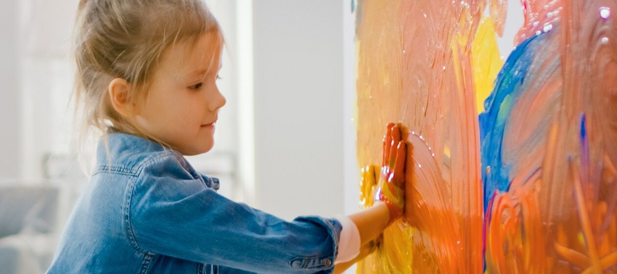 Ein Kind malt mit den Händen auf einer riesigen Leinwand