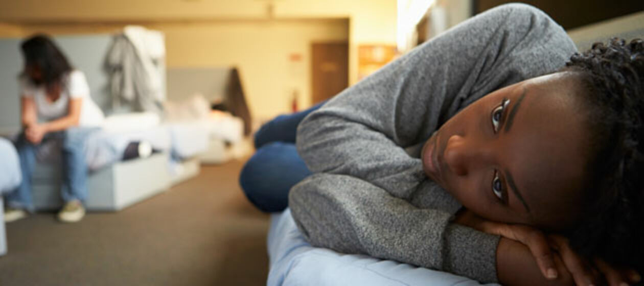 Eine junge, dunkelhäutige Frau liegt auf einem Bett in einem Asylheim