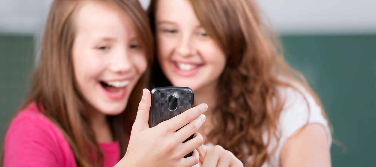 Zwei Mädchen lachend mit Smartphone
