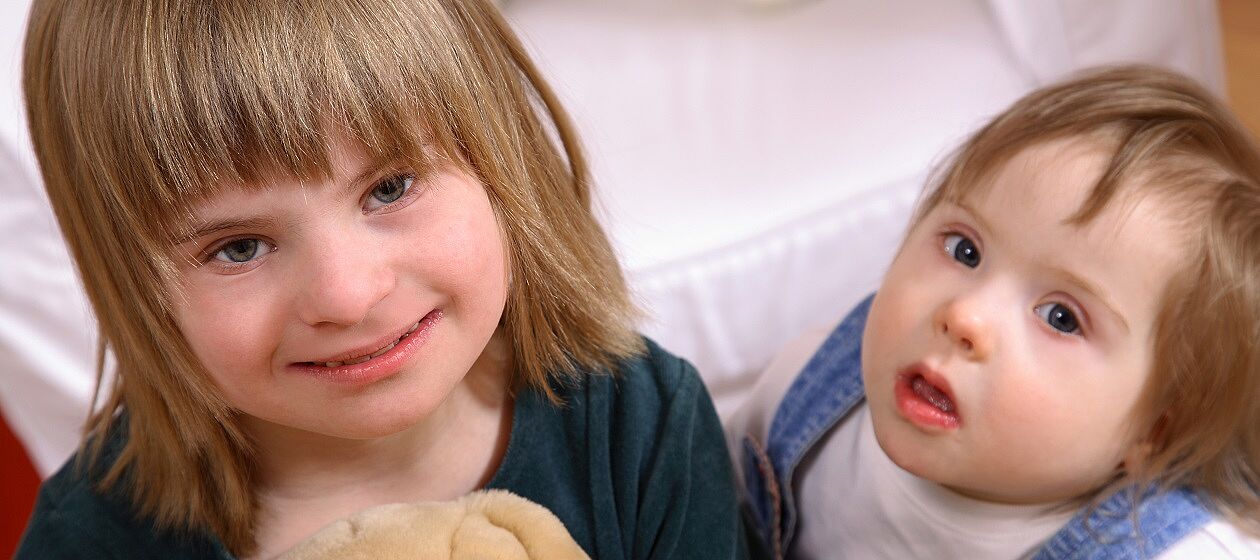 Zwei Mädchen mit Down-Syndrom (Trisomie 21) spielen.
