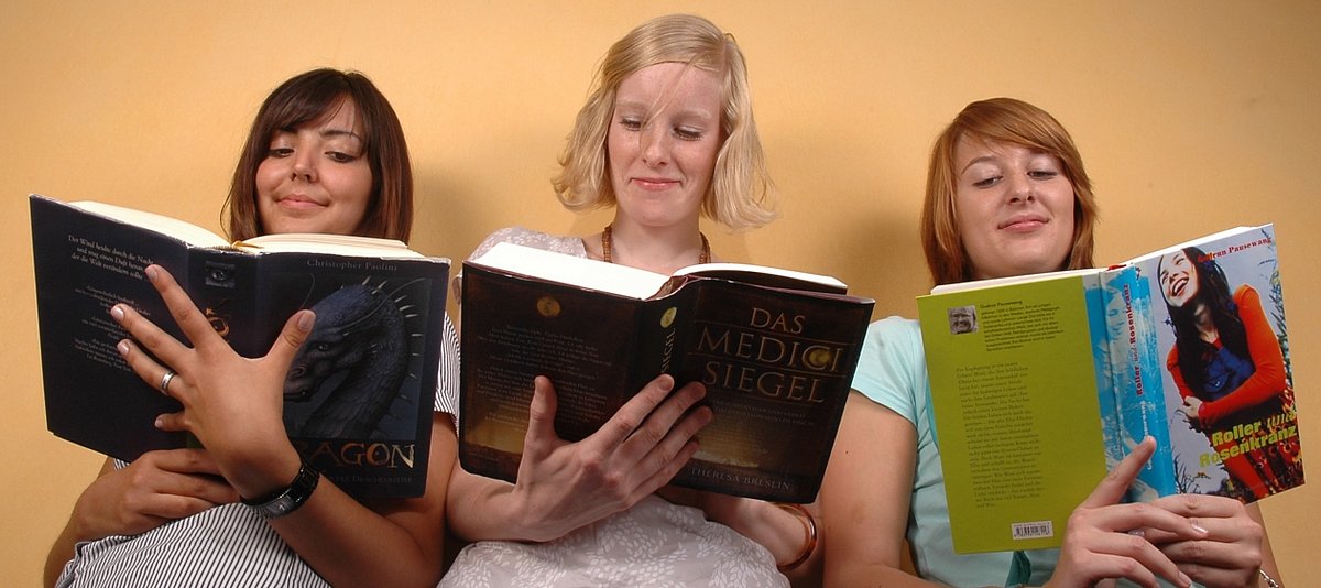 Drei Jugendliche schauen in aufgeschlagene Bücher