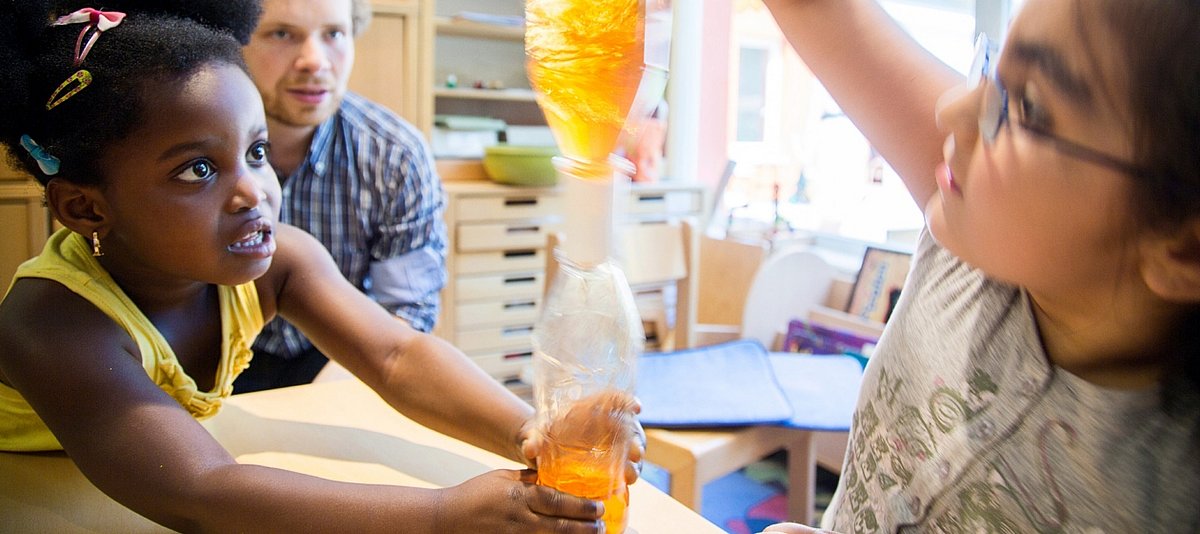 Zwei Kinder experimentieren mit einem Flaschentornado zum Thema Bewegung