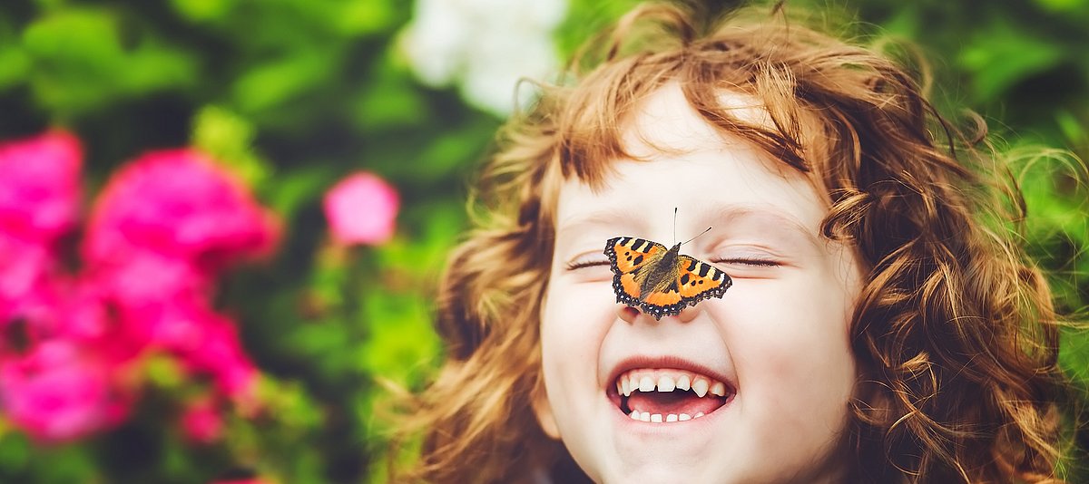 Lachendes Kind mit Schmetterling im Garten