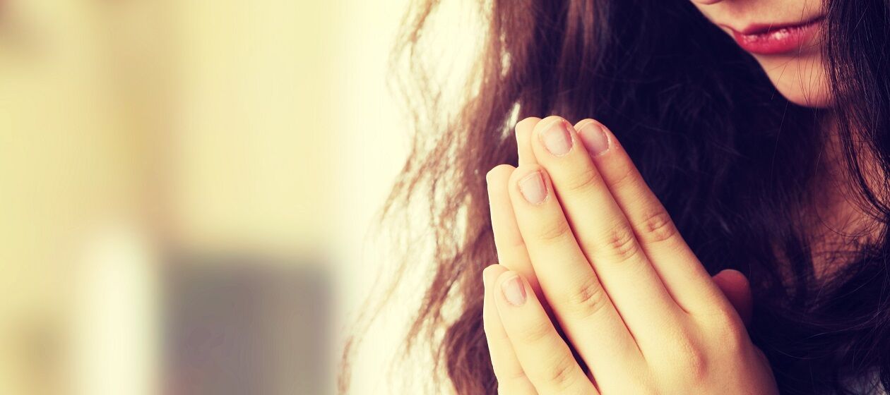 Eine junge Frau hat die Hände zum Gebet gehoben