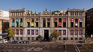 Historischer Gebäude an einer breiten Straße mit farbenfrohen Markisen an den Fenstern