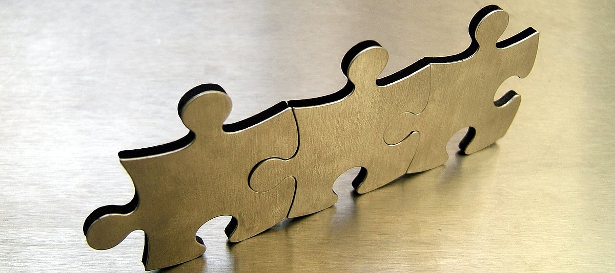 Drei Puzzleteile aus Edelstahl bilden eine Kette
