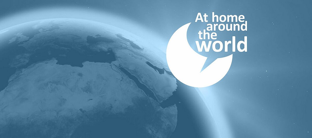 Logo der Live-Interview-Serie "At Home Around the World" vor dem Foto einer Weltkugel