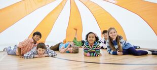 Eine Gruppe Kinder sitzt unter einem zirkuszeltartigen Tuch
