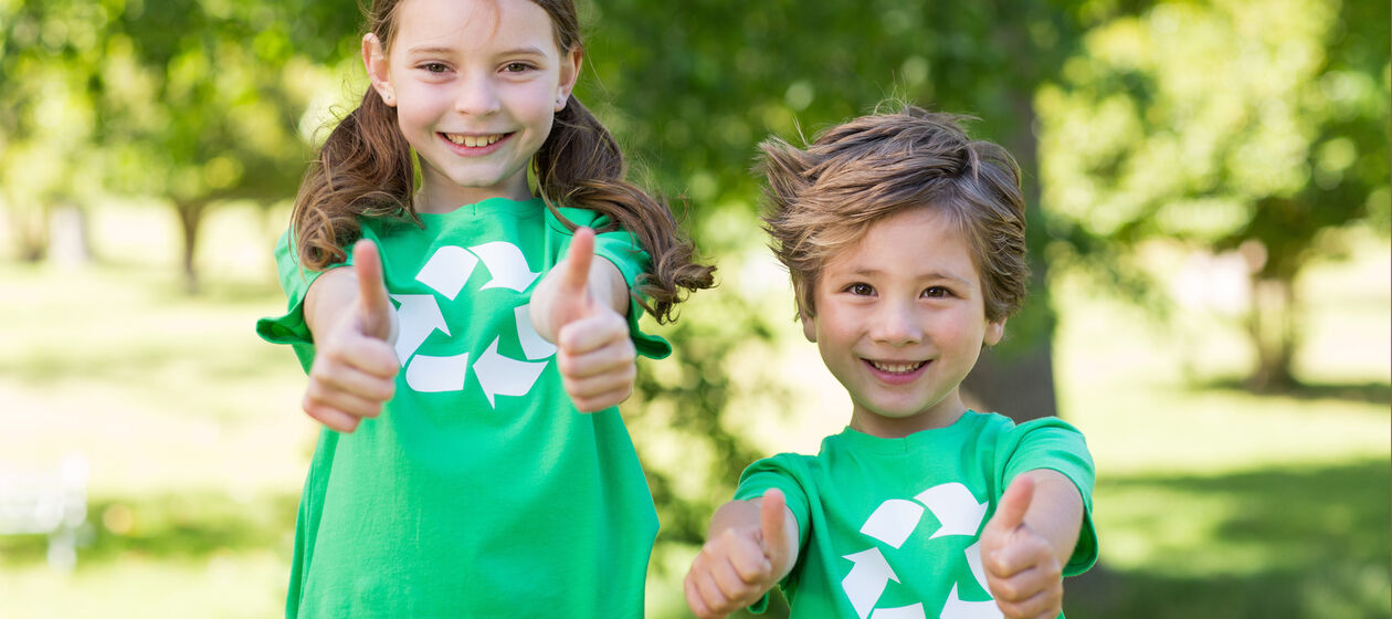Mädchen und Junge tragen T-Shirts mit Recyclingsymbol