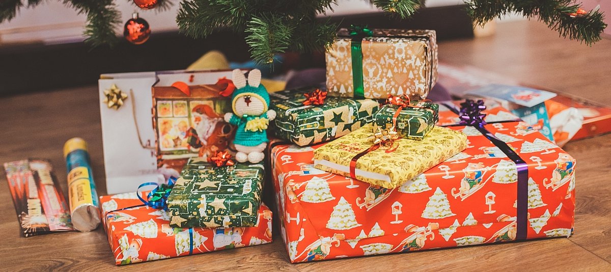 Bunte Weichnachtsgeschenke liegen unter einem geschmückten Weihnachtsbaum