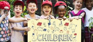 Gruppe lachender Kita-Kinder mit Plakat mit Aufschrift Children