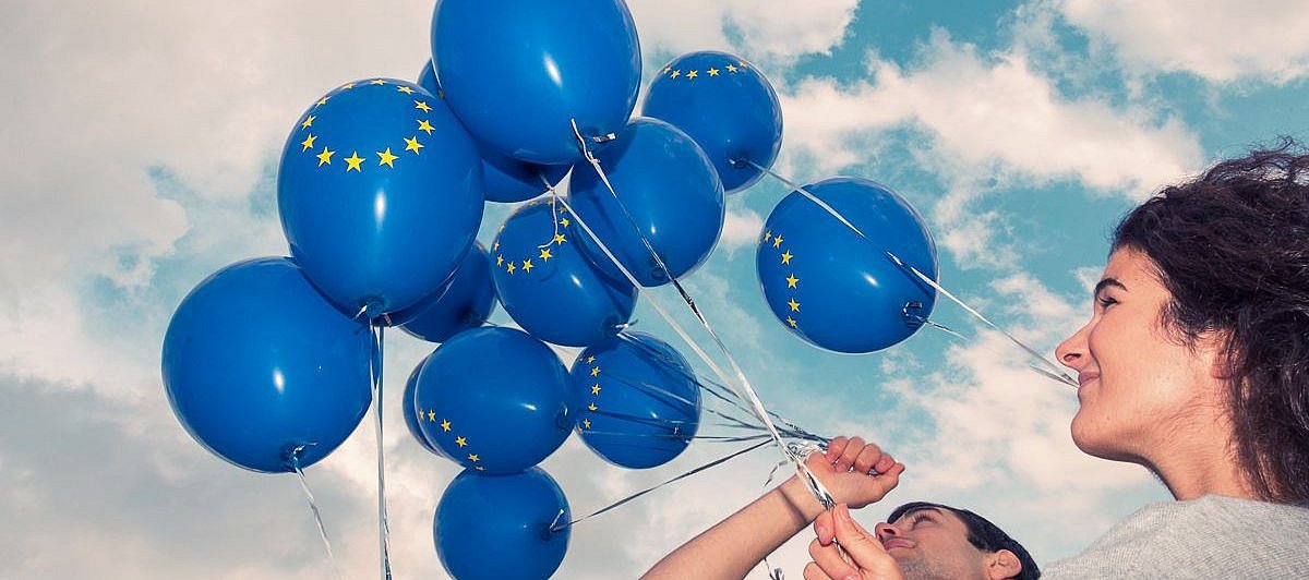 Jugendliche lassen blaue Luftballons in den Himmel aufsteigen 