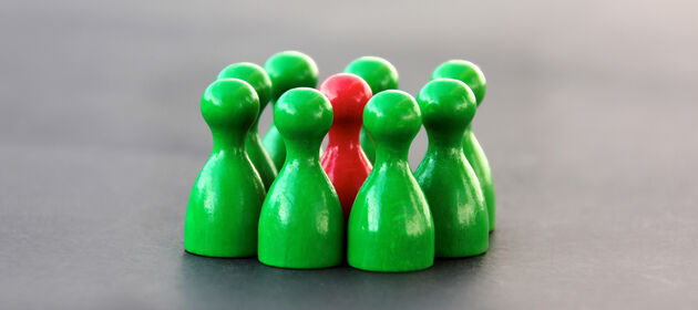 Grüne Spielfiguren stehen im Kreis um eine rote Spielfigur