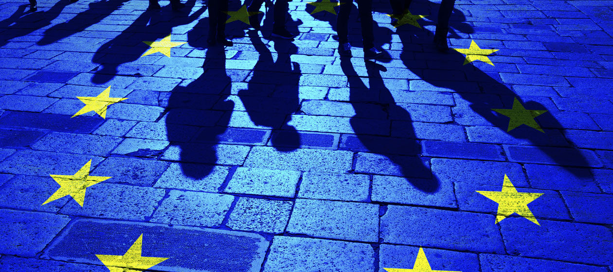 Ein Bild von Schatten einiger Personen auf der Straße mit der Europaflagge überlagert.