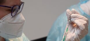 Eine Frau mit FFP2-Maske und Handschuhen bereitet eine Impfung vor