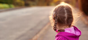Kleines Mädchen schaut eine Straße entlang