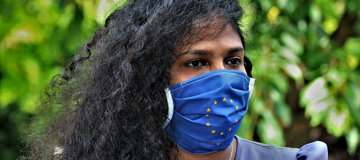 Frau trägt blaue Atemmaske mit den EU Sternen