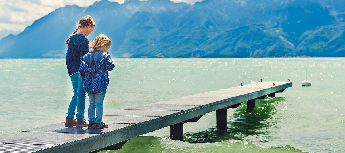 Kinder stehen auf einem Steg am See