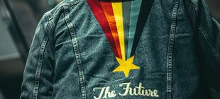 Eine Jeansjacke von hinten, mit einem Stern, der einen bunten Schweif hinter sich her zieht und der Aufschrift The Future