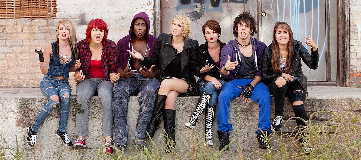 Eine Gruppe Jugendlicher sitzt in ihrer Freizeit auf einer Mauer.