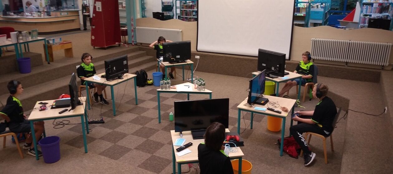 Fünf Jungen und eine Erwachsene sitzen an sechs PC-Tischen in der Stadtbibliothek Bielefeld.