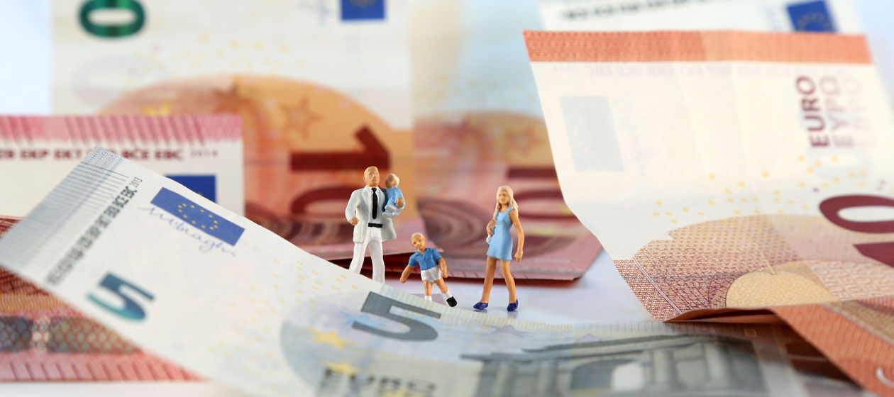 Eine Familie aus Miniatur-Figuren steht auf Euro-Scheinen.