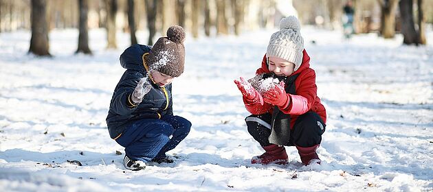Zwei Kinder spielen in einem Park im Schnee